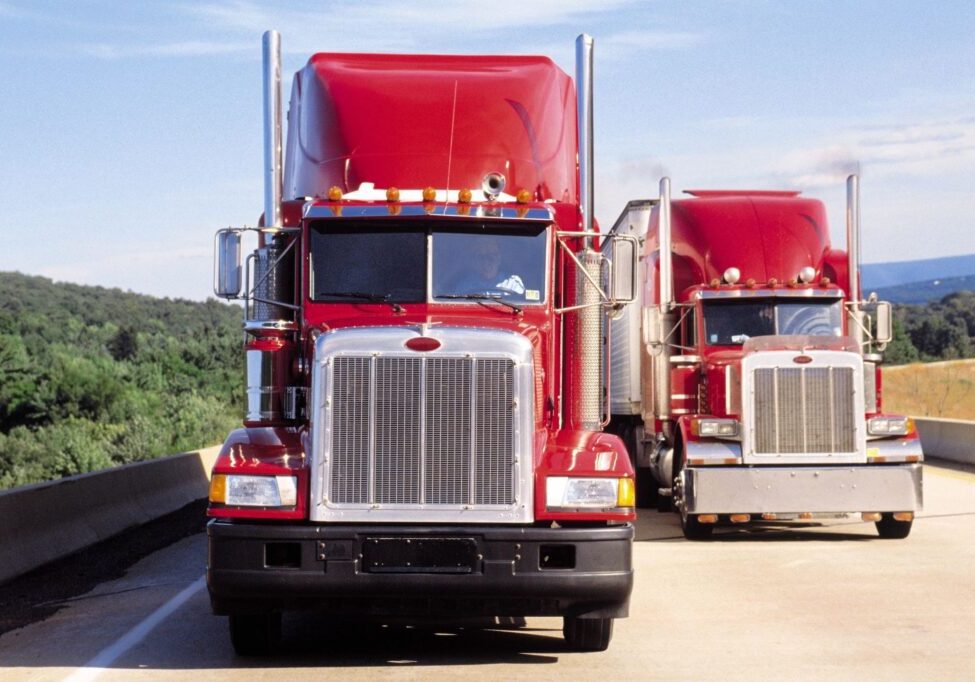 Two Red Trucks in a Row Next to Each Other